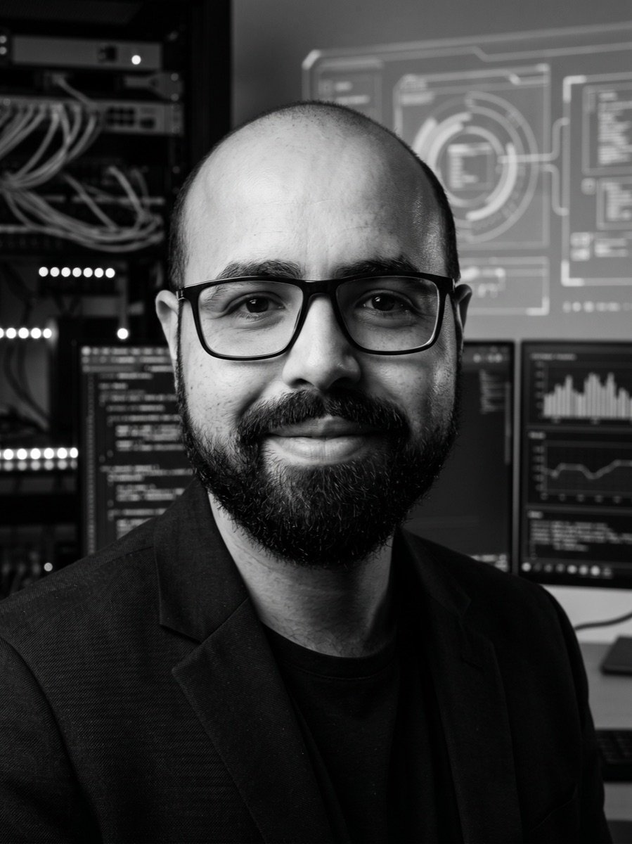 Eduardo Decussi de blazer, com racks de servidores e telas de monitoramento ao fundo